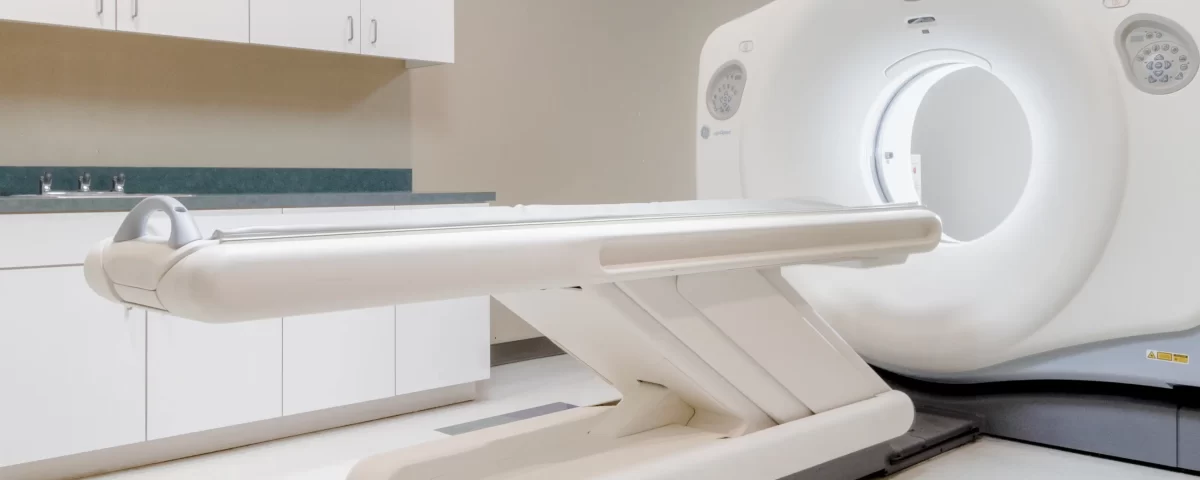 A modern CT scanner is shown in a clean, empty medical imaging room with white cabinets and tiled flooring, providing advanced diagnostic services for Dallas patients.