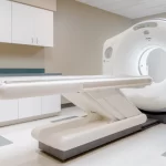 A modern CT scanner is shown in a clean, empty medical imaging room with white cabinets and tiled flooring, providing advanced diagnostic services for Dallas patients.