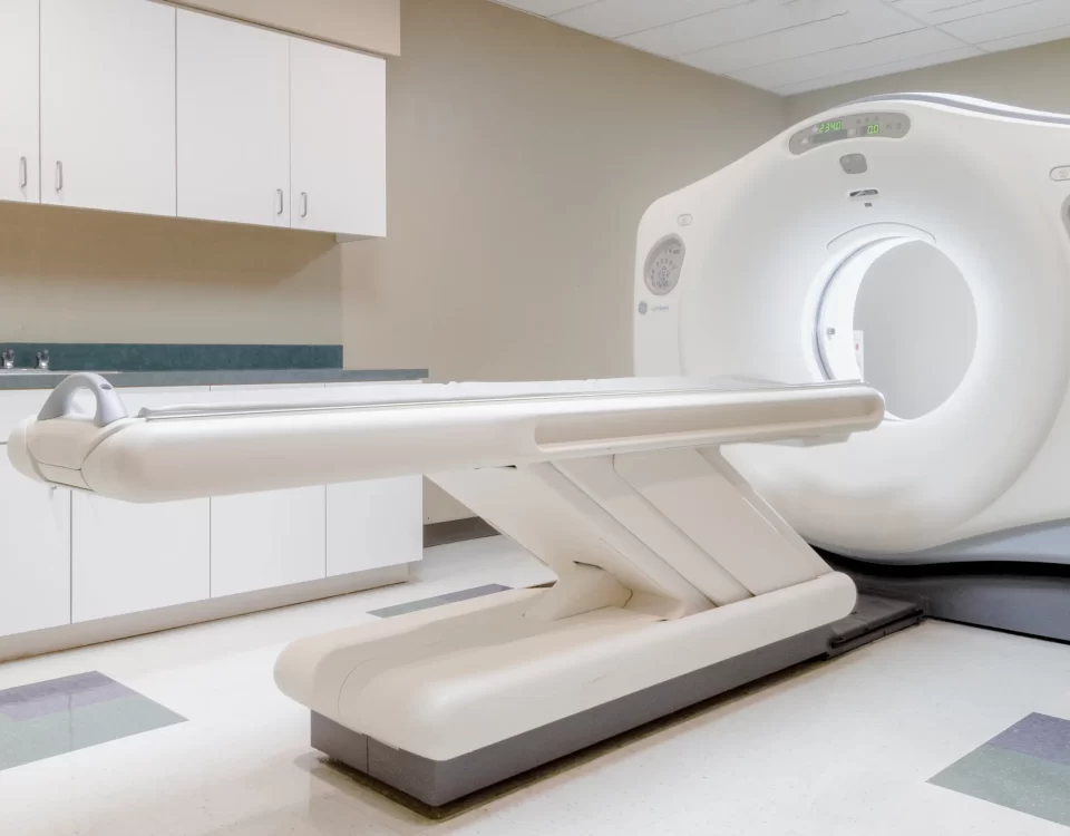 A modern CT scanner is shown in a clean, empty medical imaging room with white cabinets and tiled flooring, providing advanced diagnostic services for Dallas patients.
